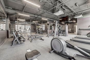 a gym with weights and cardio equipment at the district at highland village apartments